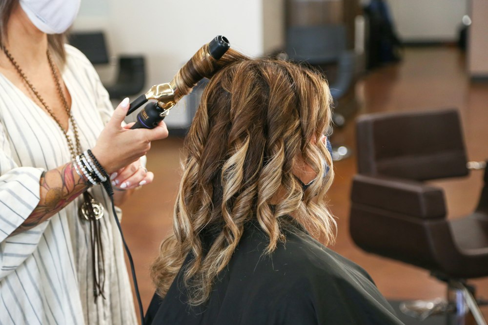 Stylist curling a client's hair in a salon